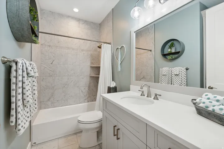 Full bathroom featuring a white vanity with an integrated sink, brushed nickel faucet, and a large mirror