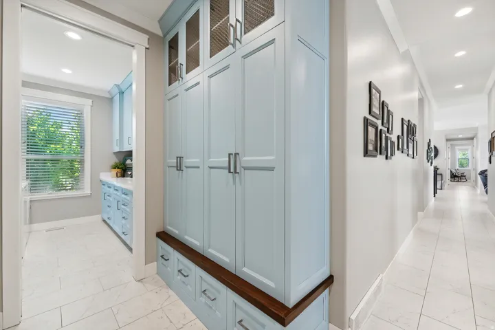 Built-in cabinetry with light blue shaker-style doors, glass-front upper cabinets, and a dark wood-finish bench