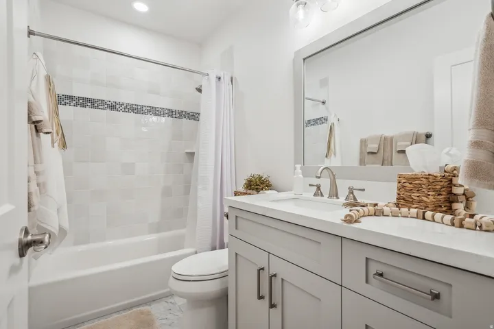 Bathroom featuring a tub/shower combination with mosaic tile accent band