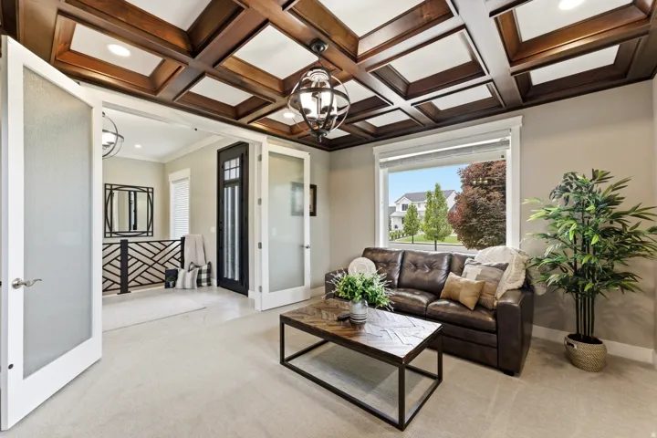 Coffered ceiling with recessed lighting and a central chandelier