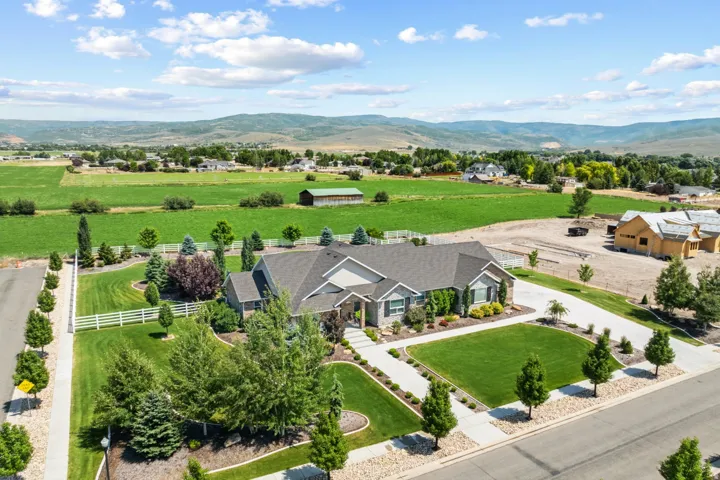 Expansive property featuring a stone and siding exterior, a wide concrete driveway, and mature landscaping