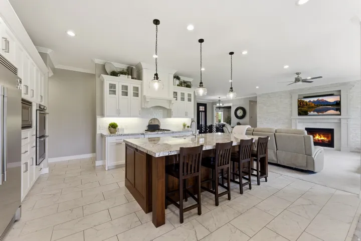 Open-concept kitchen featuring a large island with seating, stainless steel appliances, white cabinetry, and recessed lighting