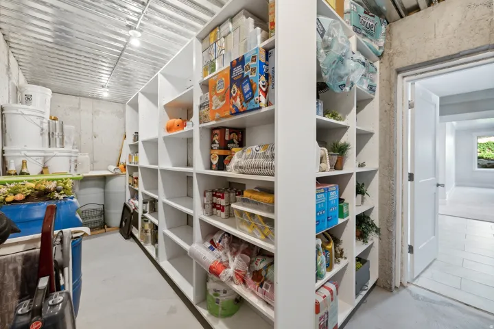 Extensive built-in white shelving providing substantial storage, concrete walls, and a corrugated metal ceiling