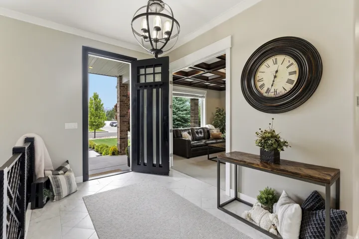 Entryway featuring marble-look tile flooring, an open-concept layout, a black metal spindle railing, a contemporary spherical chandelier, and a substantial black entry door