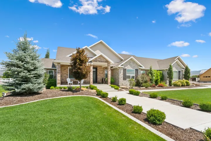 Spacious ranch-style residence featuring a brick and stone facade, gabled rooflines, and a covered entry