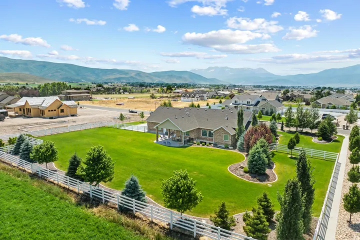 Expansive green lawn with mature landscaping and white picket fencing