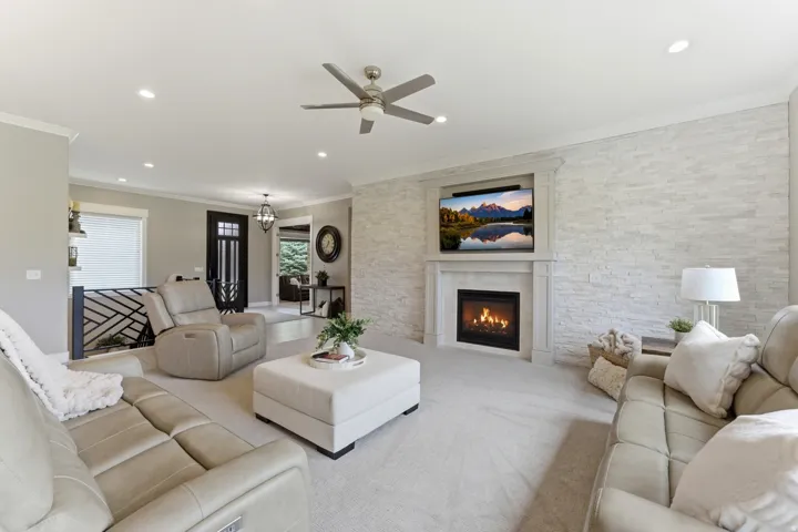 Living area with a stacked stone accent wall featuring a built-in fireplace and media niche