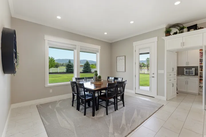 Spacious dining area featuring large windows showcasing mountain scenery, a glass-paneled exterior door, recessed lighting, and tile flooring