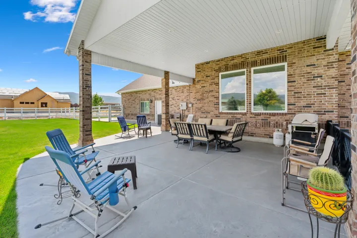Expansive covered patio featuring brick columns, a concrete surface, and a white soffit ceiling