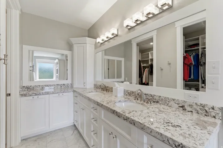 Dual vanity featuring white cabinetry and light-toned granite countertops