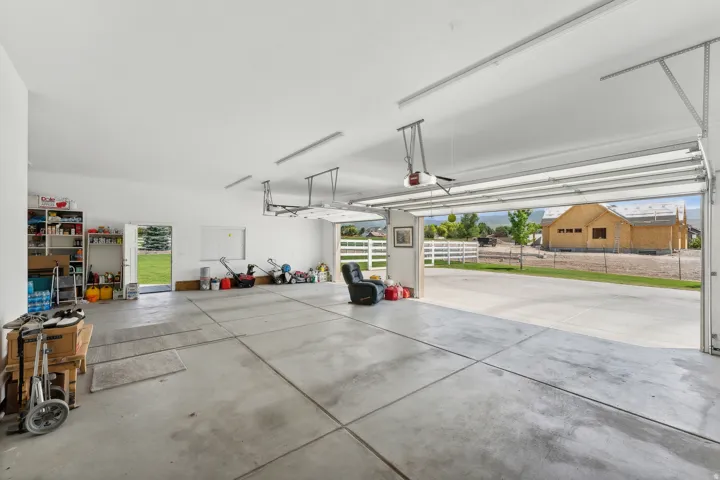 Spacious three-car garage with concrete flooring and multiple overhead garage door openers