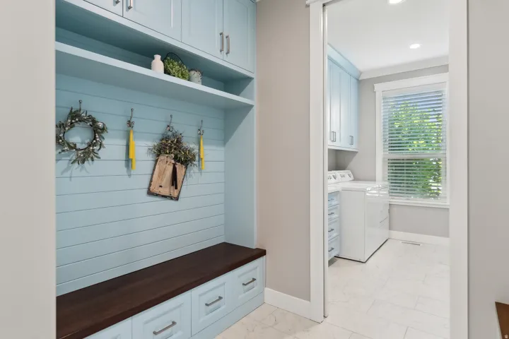 Built-in bench with a dark wood-finish top and integrated drawers, shiplap wall paneling, and upper shelving in a light blue finish