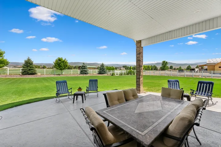 Expansive concrete patio under a covered porch featuring a stone-clad support pillar