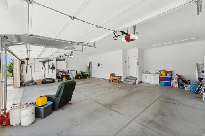 Spacious three-car garage featuring a concrete floor, white walls, and bright overhead lighting