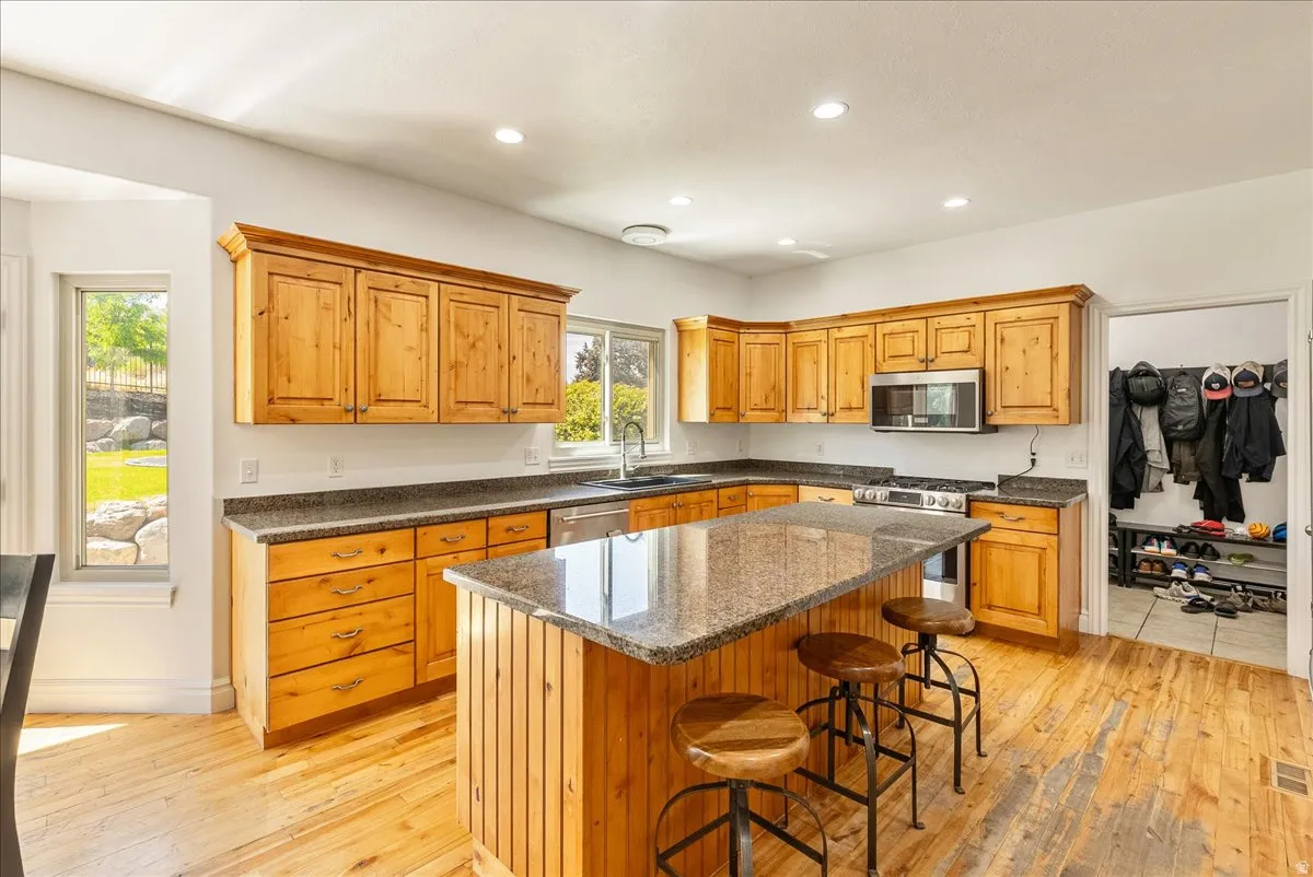 Spacious kitchen featuring natural wood cabinetry, granite countertops, and wood-finish flooring