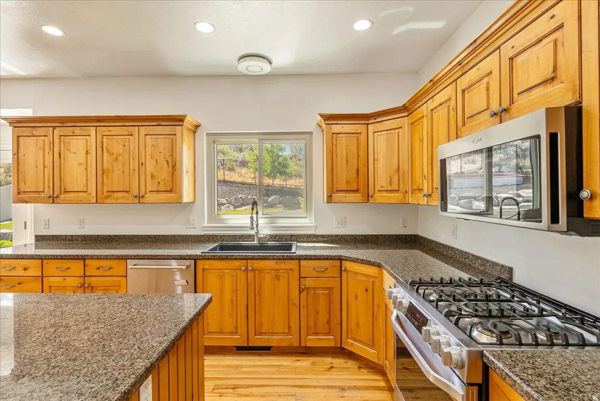 Spacious kitchen featuring light wood cabinetry, granite-style countertops, stainless steel appliances, and a window above the sink