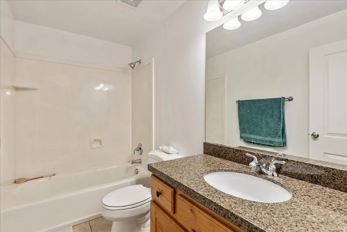 Bathroom featuring a vanity with a granite-style countertop, undermount sink, and wood-finish cabinetry