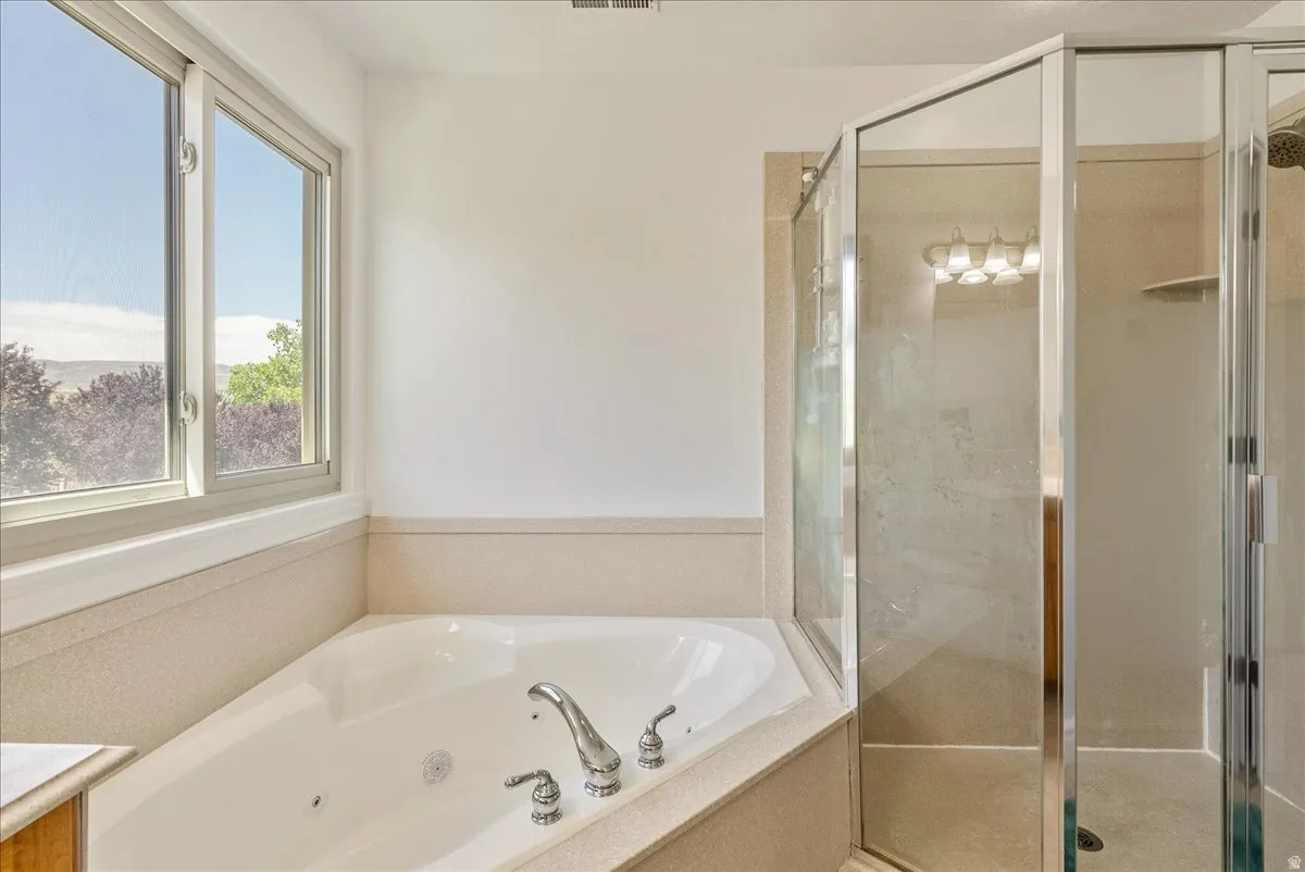Soaking tub with chrome fixtures, surrounded by a light-colored countertop