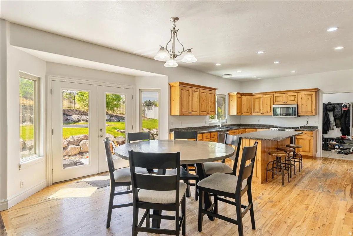 Open-concept kitchen and dining area featuring wood-finish flooring, recessed lighting, and a chandelier