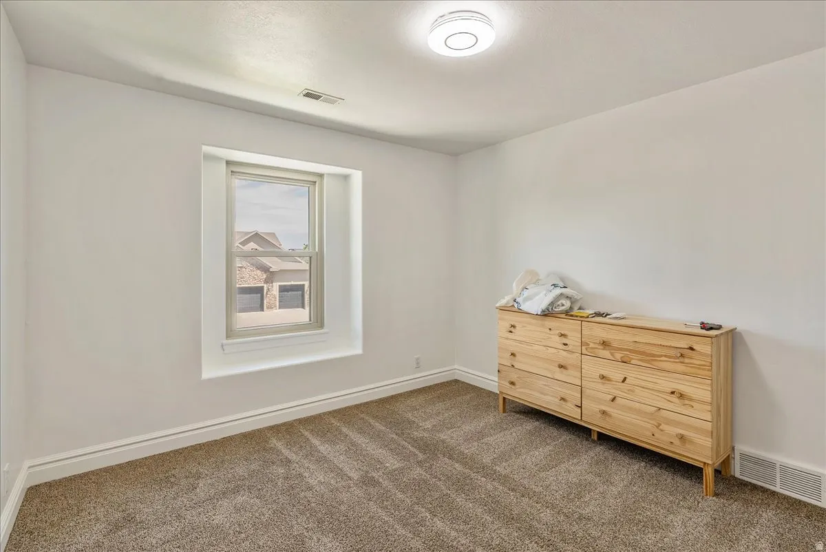 White walls with carpet flooring, trim molding, and a single window