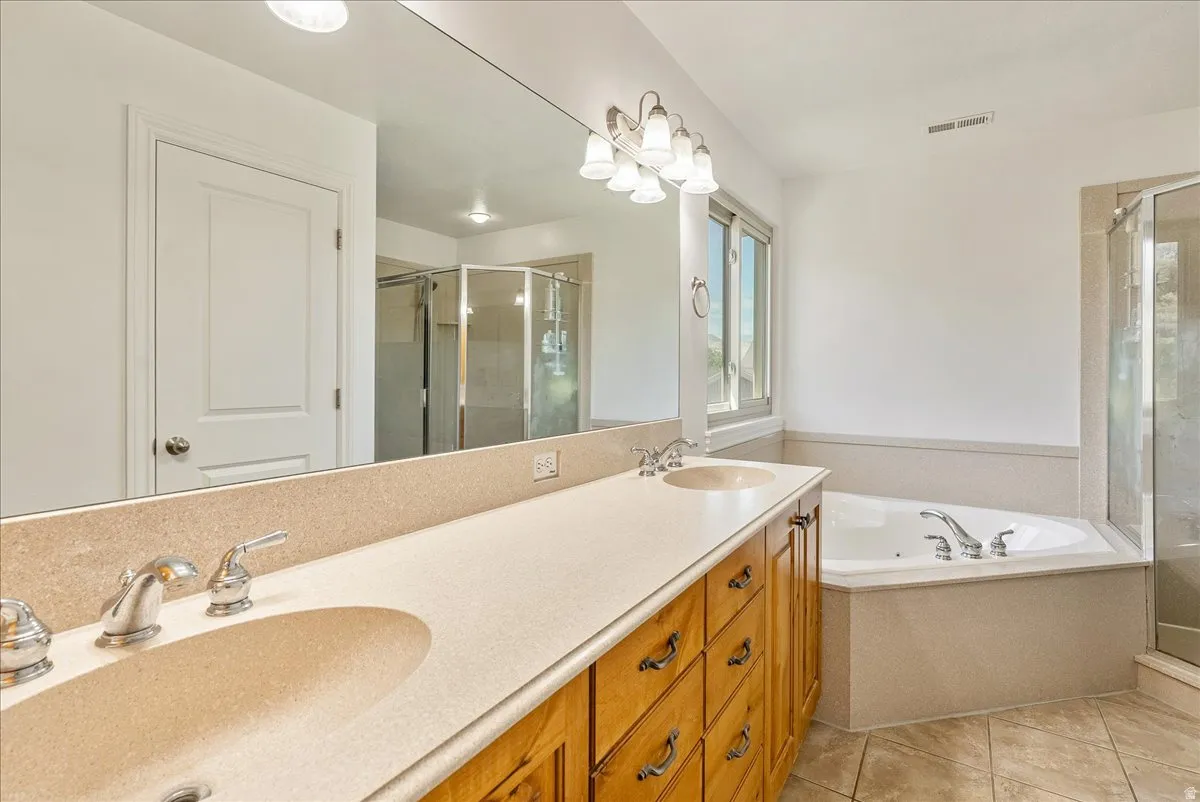 Bathroom featuring a double vanity with integrated sinks, a corner soaking tub, and a separate glass-enclosed shower
