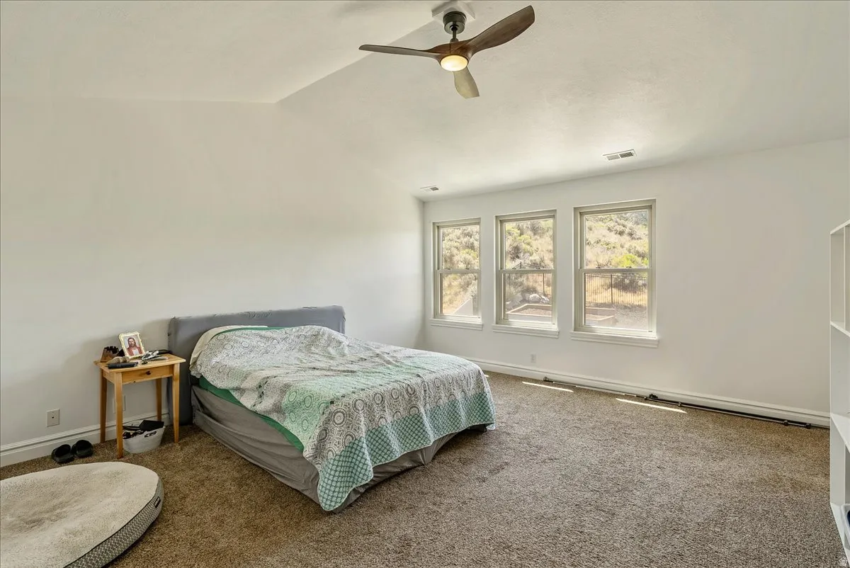 Carpeted room with a vaulted ceiling and a ceiling fan with integrated lighting
