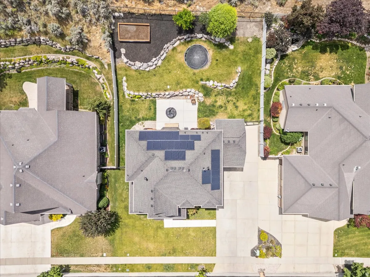 Expansive backyard featuring a manicured lawn, established landscaping, and a patio with a built-in fire pit