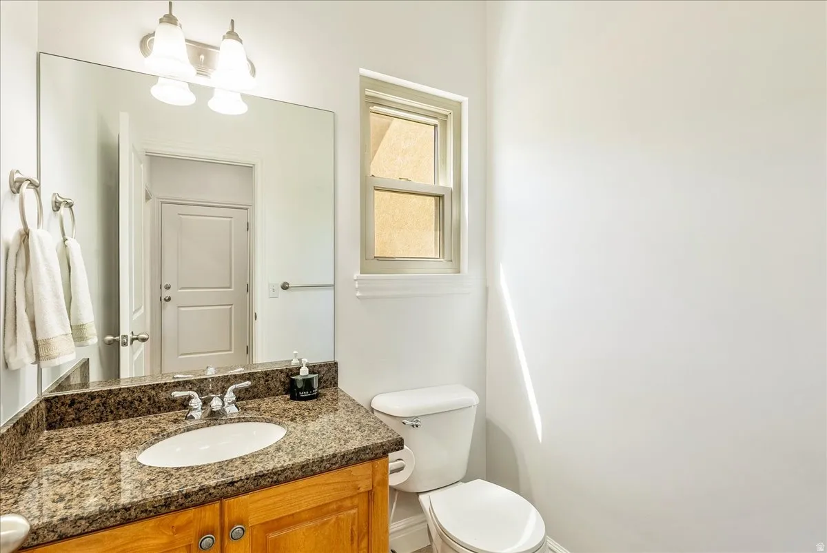 Bathroom vanity featuring a polished stone countertop, undermount sink, and wood cabinetry