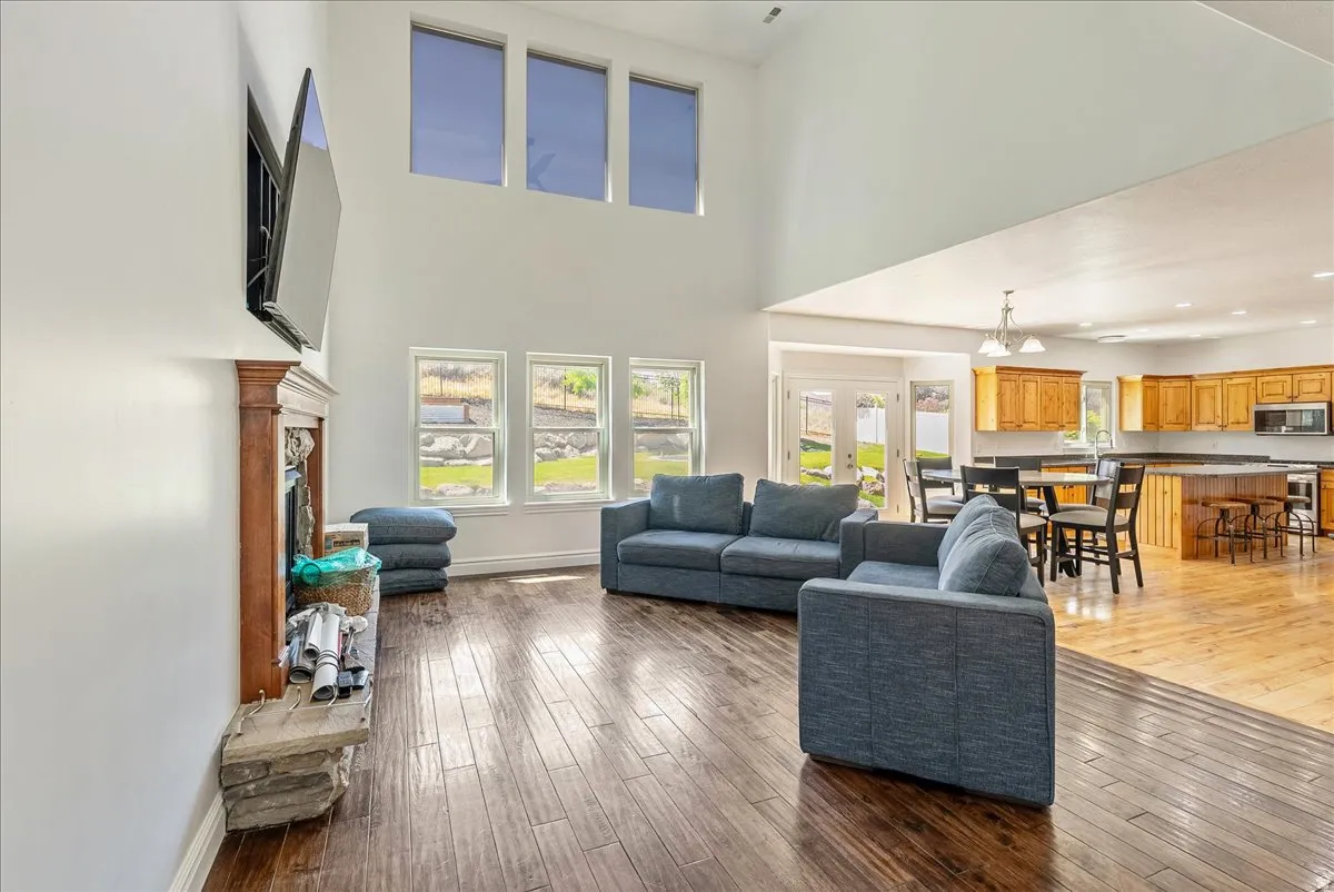 Living area with high ceilings, wood-finish flooring, and multiple windows providing natural light