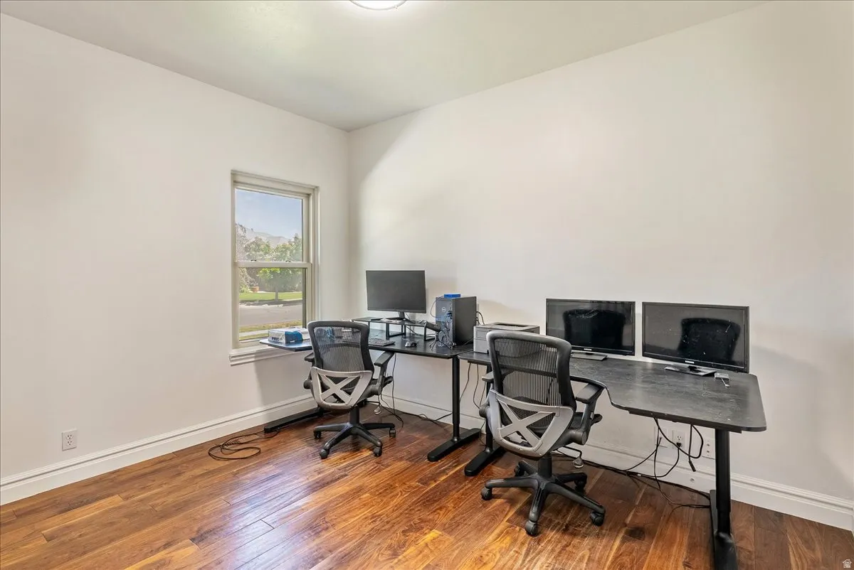 Room featuring wood-finish flooring, a single window with white trim, and white painted walls