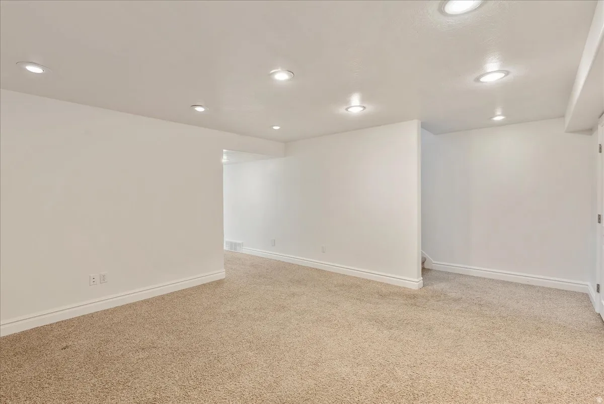 Recessed lighting illuminates the carpeted room, featuring white baseboards and walls