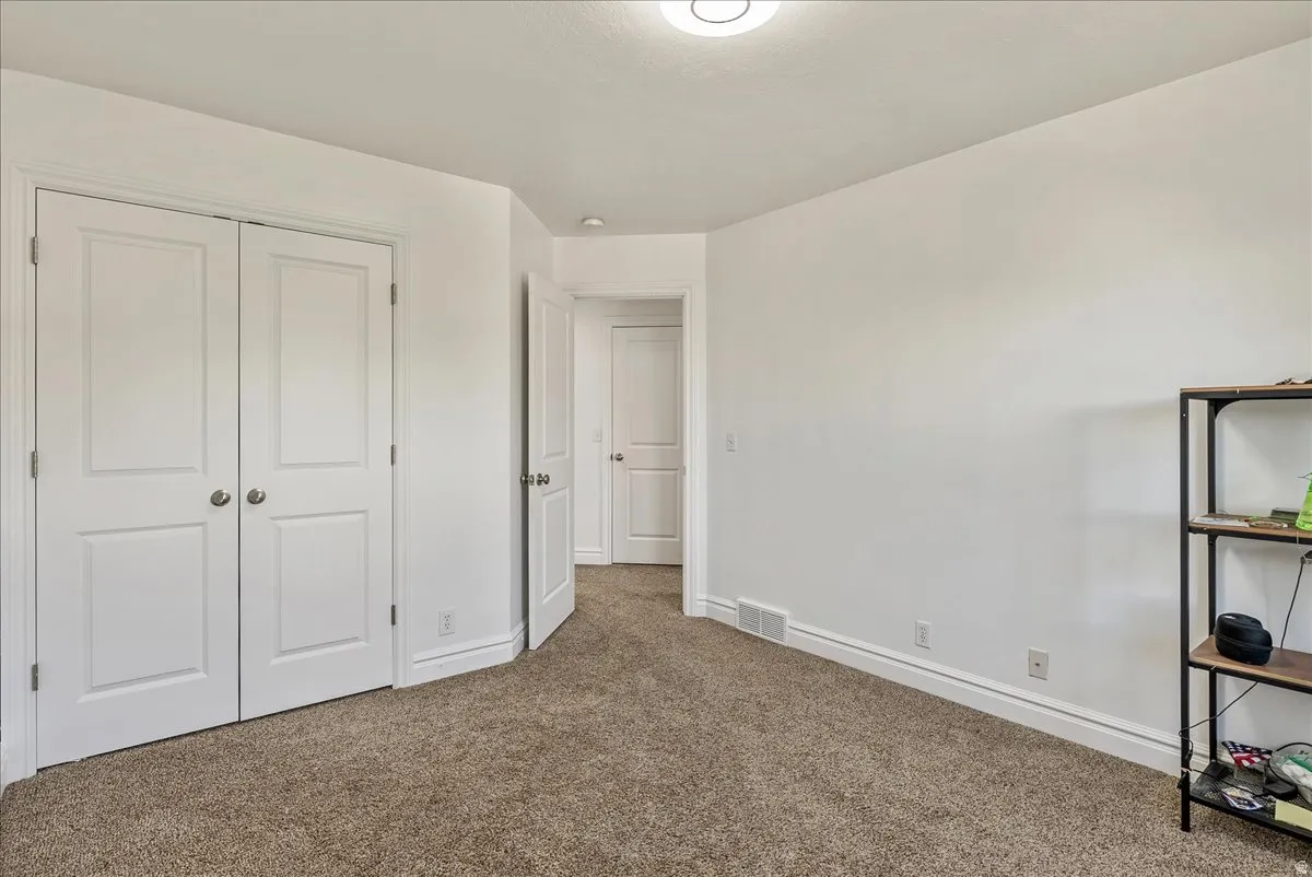 Carpeted room featuring a double-door closet with paneling, white walls, white baseboards, and a flush-mount ceiling light