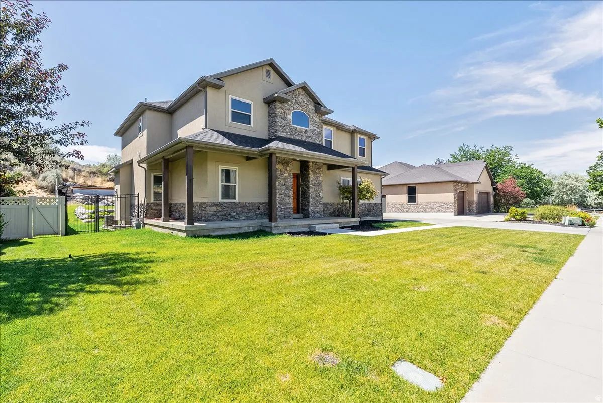 Two-story stucco exterior featuring stone accents and a covered front porch
