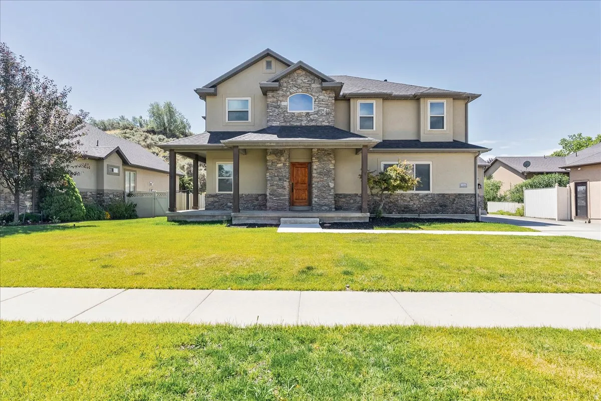 Two-story stucco and stone residence featuring a covered front porch with dark wood columns