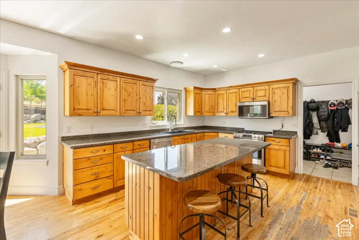Spacious kitchen featuring natural wood cabinetry, granite countertops, and wood-finish flooring