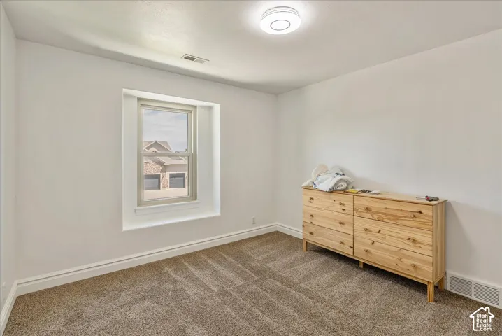 White walls with carpet flooring, trim molding, and a single window