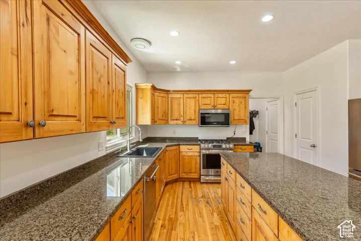 Kitchen featuring a long center island, wood-finish flooring, recessed lighting, and ample natural wood cabinetry with stone countertops