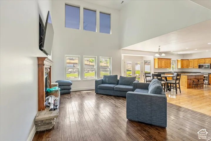 Living area with high ceilings, wood-finish flooring, and multiple windows providing natural light