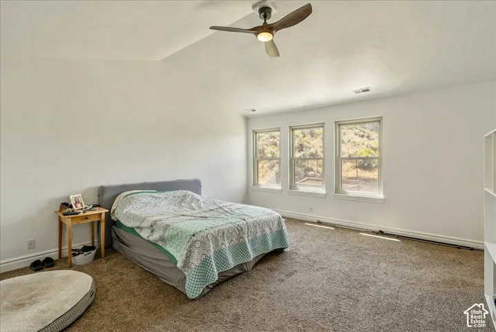 Carpeted room with a vaulted ceiling and a ceiling fan with integrated lighting