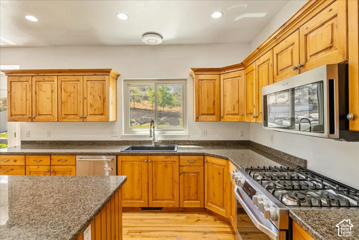 Spacious kitchen featuring light wood cabinetry, granite-style countertops, stainless steel appliances, and a window above the sink