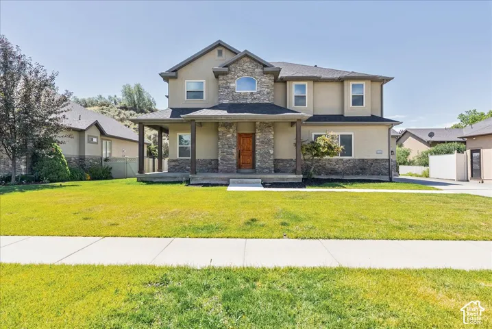 Two-story stucco and stone residence featuring a covered front porch with dark wood columns