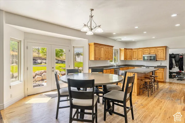 Open-concept kitchen and dining area featuring wood-finish flooring, recessed lighting, and a chandelier