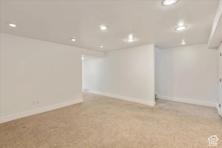 Recessed lighting illuminates the carpeted room, featuring white baseboards and walls