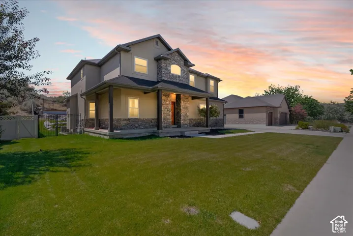 Stucco and stone facade with a covered front porch, an attached garage, and a detached two-car garage