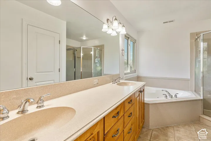 Bathroom featuring a double vanity with integrated sinks, a corner soaking tub, and a separate glass-enclosed shower