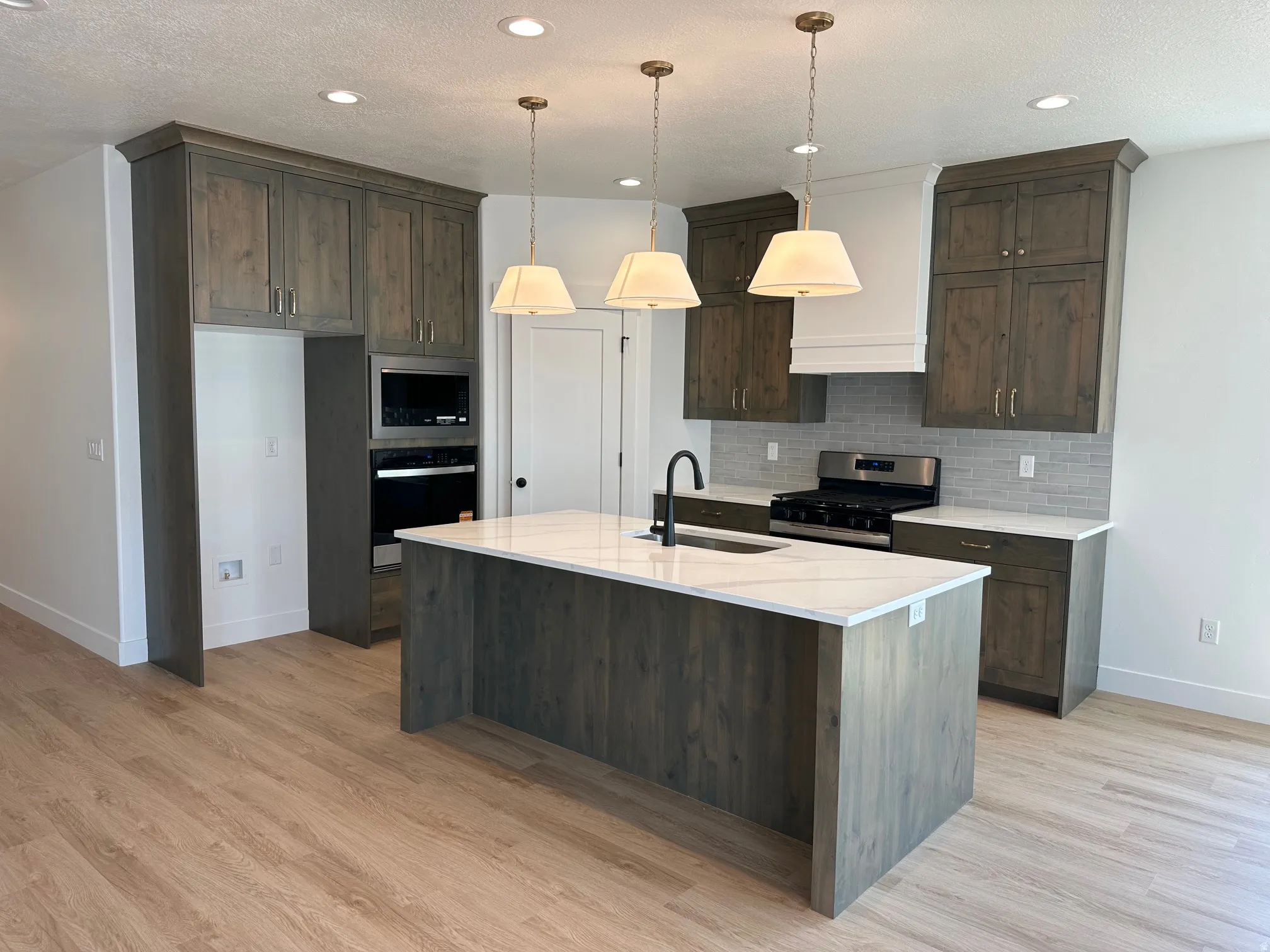 Kitchen featuring wood-finish flooring, a central island with a light-toned countertop, and recessed lighting