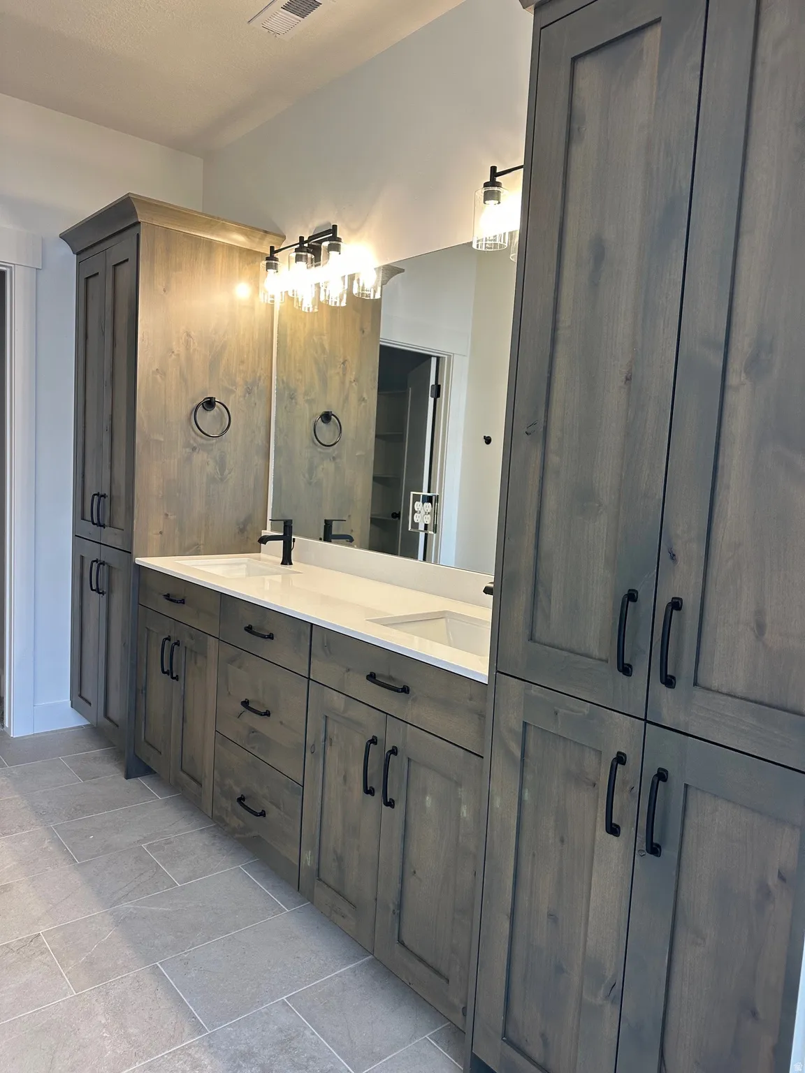 Dual vanity with integrated sinks, white countertop, dark wood-finish cabinetry, and tiled flooring