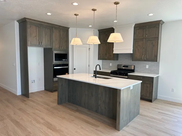 Kitchen featuring wood-finish flooring, a central island with a light-toned countertop, and recessed lighting