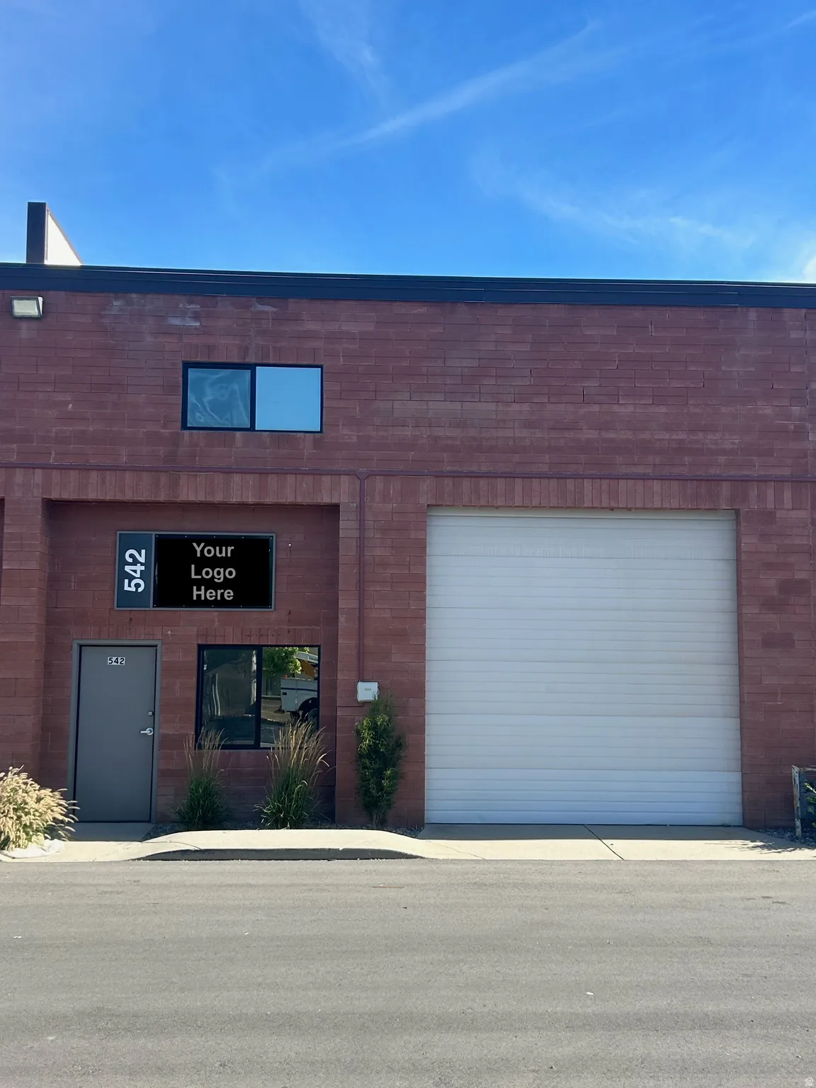 Brick facade commercial building featuring an overhead garage door, a pedestrian door, and multiple windows