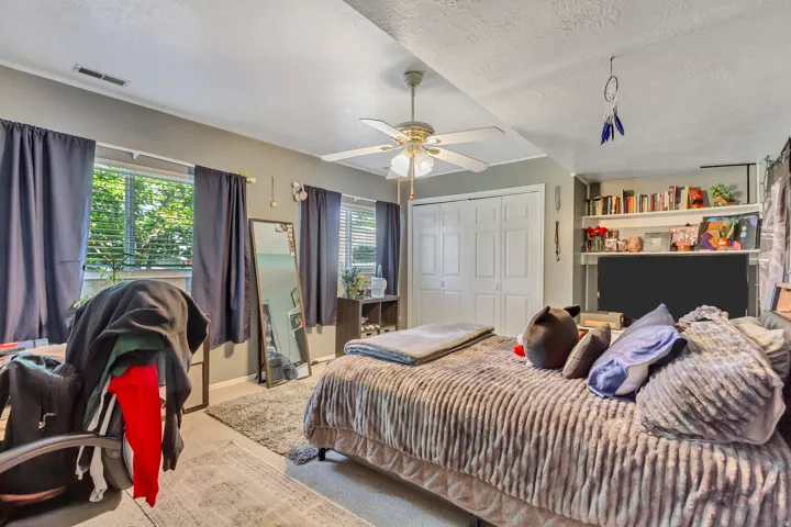 Bedroom featuring multiple windows, a ceiling fan with integrated lighting, bi-fold closet doors, and built-in shelving
